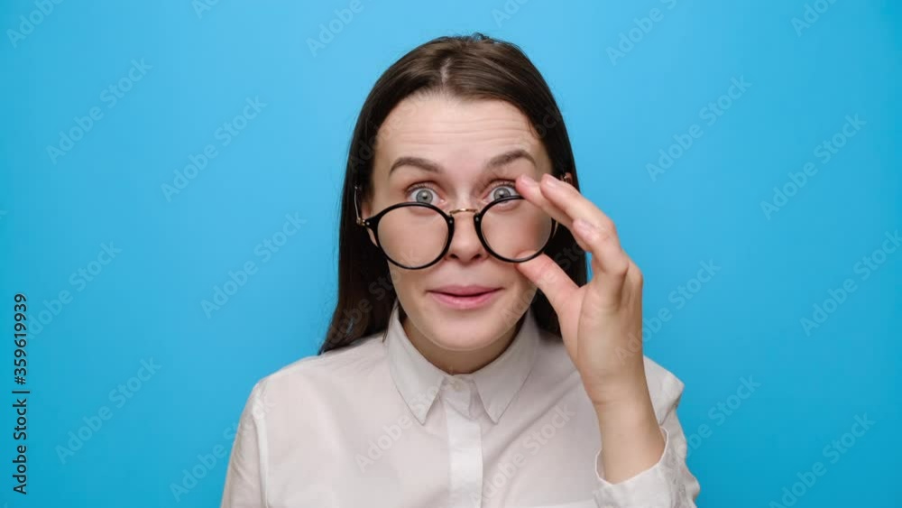 Shocked brunette woman take off glasses look at camera stunned with deal or offer, amazed young girl feel surprised by unexpected news, dressed in white shirt, isolated on blue studio background Shocked brunette woman take off glasses look at camera stunned with deal or offer, amazed young girl feel surprised by unexpected news, dressed in white shirt, isolated on blue studio background