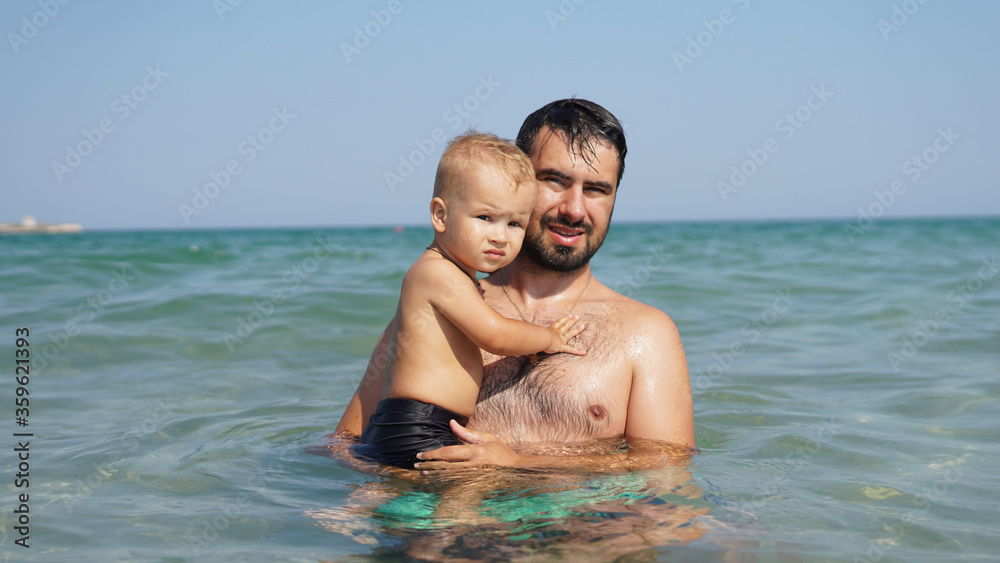 Little happy kid and his smiling father in sea. Dad holding boy