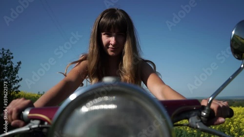 Girl on a retro motorcycle, the girl looks at the camera. Close-up