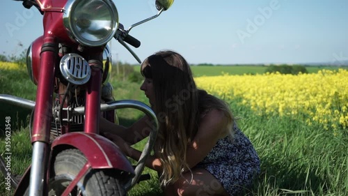 The girl repairs the motorcycle, adjusts the carburetor, the girl adjusts the retro motorcycle