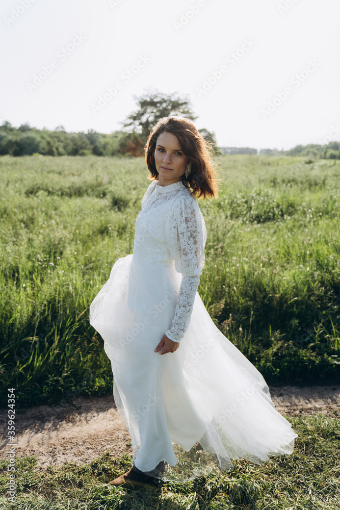 beautiful woman in long white dress posing in the field 