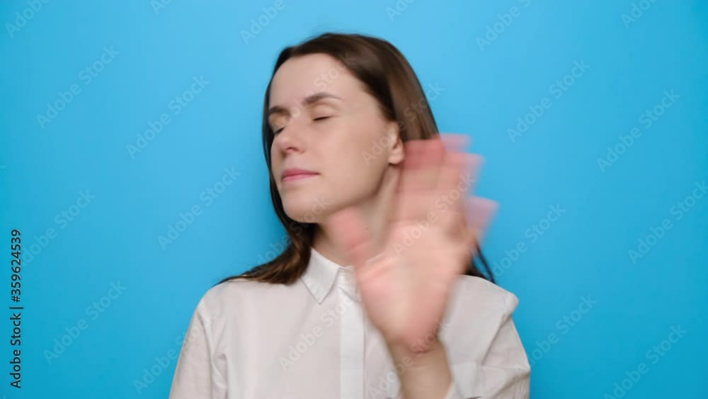 Portrait of young girl looking at camera waving hands do not wanna listen showing stop gesture, dressed in white shirt, isolated on blue studio background. People sincere emotions lifestyle concept Portrait of young girl looking at camera waving hands do not wanna listen showing stop gesture, dressed in white shirt, isolated on blue studio background. People sincere emotions lifestyle concept