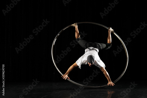 Man in circle. Circus performer artist in a Cyr Wheel (Roy Cyr) in theatre at a black background photo