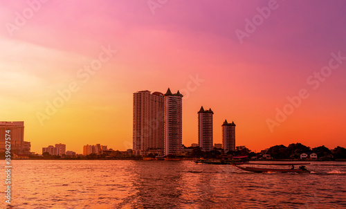 Dramatic sunset on river with building and boat in Chaophraya river, Bangkok, Thailand © NtDanai