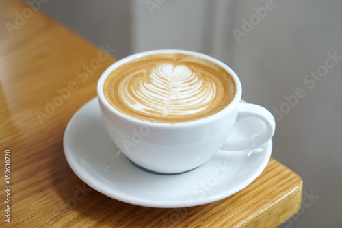 Hot Latte - A cup of coffee with milk and beautiful leaf pattern latte art on wooden table and copy space, Perfect for breakfast time.