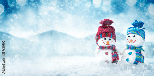 Two happy snowman hold hands in winter scenery with copy space. Christmas background