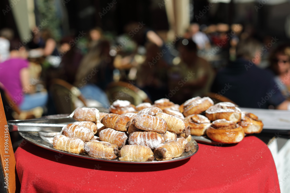 Pastry in focus on a tray near restaurant on the street, people are blurred Pastry in focus on a tray near restaurant on the street, people are blurred
