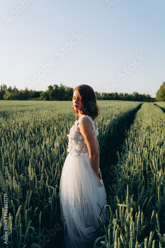 back view of woman in long white dress standing in the field 