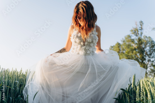 attractive woman wearing veil and long white dress standing in the field