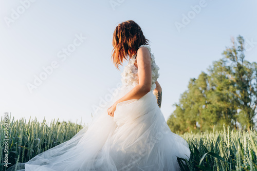 attractive woman wearing veil and long white dress standing in the field