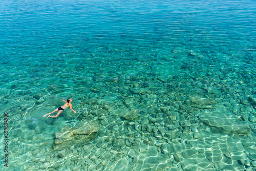 A woman swims in blue sea water in the bay. Nature and relaxation, top view © olezzo