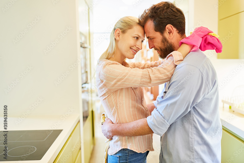 Happy couple hugs each other while doing housework Happy couple hugs each other while doing housework