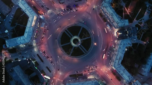 Drone spin over the intersection. Beautiful night lighting. Flight over the city. Traffic circle. Roads form a circle in architecture. View from above. Night city.