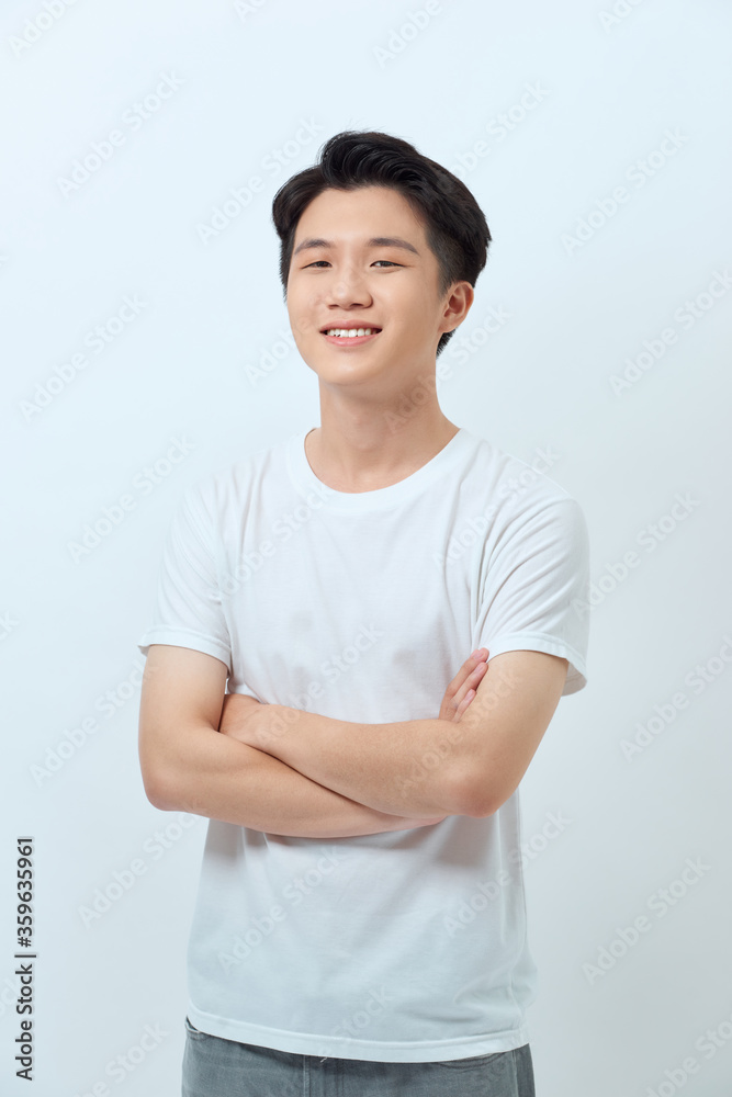 Waist-up portrait of confident Asian man standing against white wall with arms crossed Waist-up portrait of confident Asian man standing against white wall with arms crossed