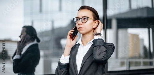 A business woman talking on the phone in the city during a working day waiting for a meeting. Discipline and timing. An employee goes towards a corporate meeting.