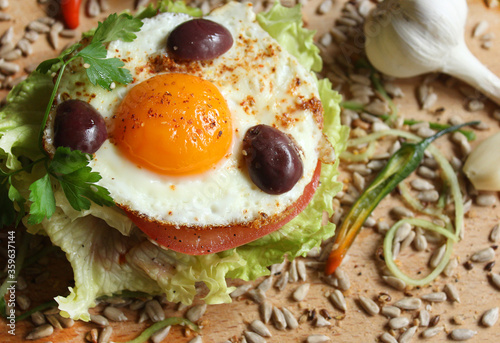 A sandwich with egg  lettuce  tomato  olives and seeds