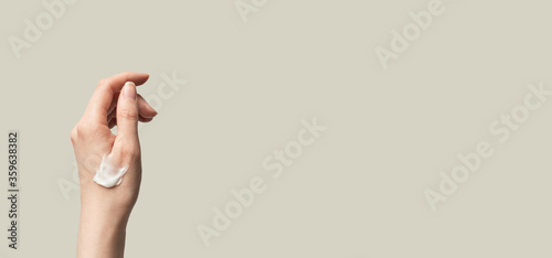 Smear smudge moisturizer cream on female hand up isolated on olive beige background horizontal banner format with copy space. Daily skincare and body care routine. Template for beauty product