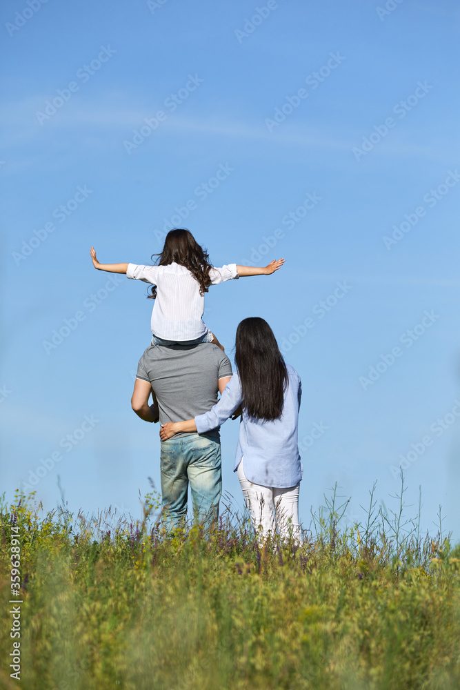 happy family father, mother and cute child girl having fun and playing in nature. daughter sits on father shoulders happy family father, mother and cute child girl having fun and playing in nature. daughter sits on father shoulders