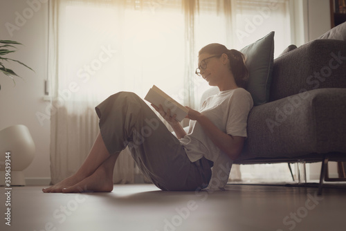 Happy woman sitting on the floor and reading a book