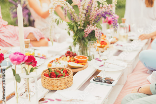 A beautiful summer picnic for girls with tasty snacks, cheese, fruits, strawberry berries, white wine and cold lemonade. Food and drink concept. Friendship and fun, Flowers decoration. Selective focus