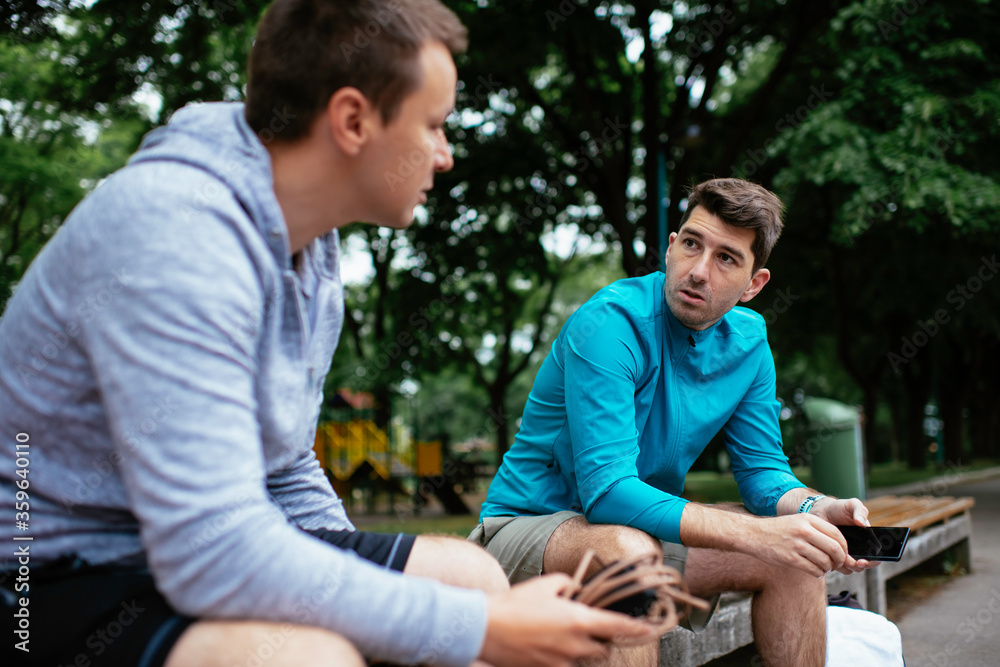 Fit young men taking rest from running. Two friends training outdoors. Fit young men taking rest from running. Two friends training outdoors.