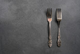 Cutlery forks isolated on a grey marble background. The minimalist monochrome photograph of the dish.