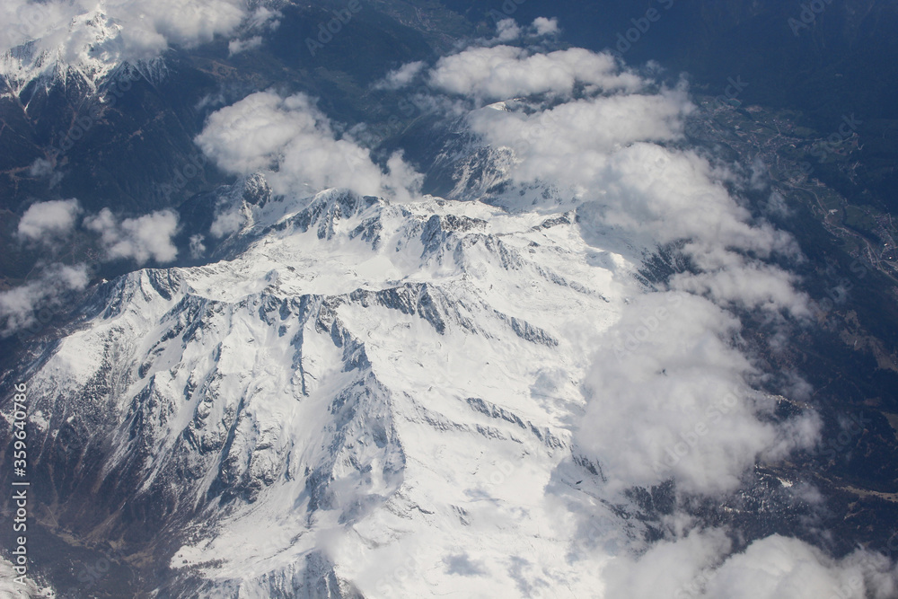 Widok z samolotu. Alpejski góry. Śnieg i puchaty chmury.