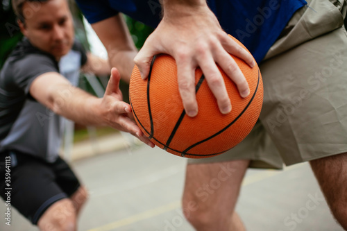 Close up of hands holding ball. Friends playing basketball in the park.	