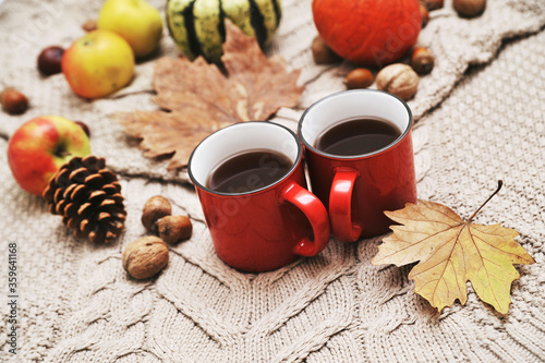 Autumn background. Pumpkins, apples, nuts,leaves, cups and sweater on wooden background.