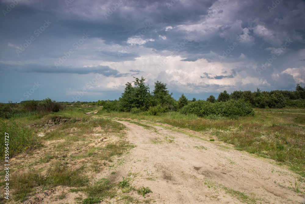 Road in field and stormy clouds