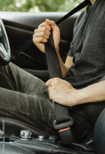 A man's hand is using a car seat belt for safety while driving a private car and preventing danger from a car accident. photo