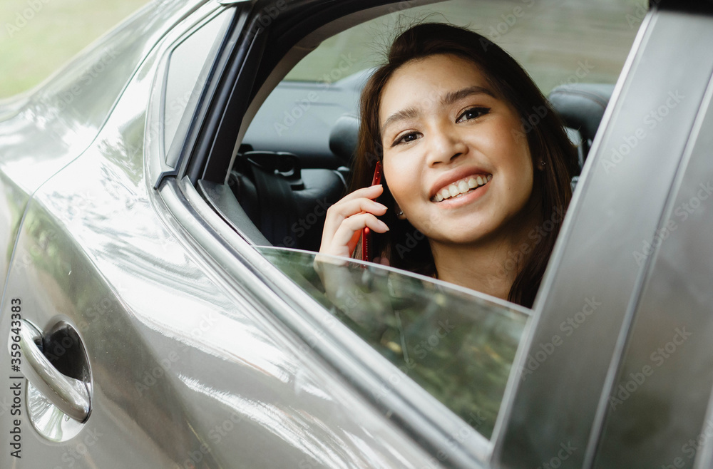Portrait of an Asian businesswoman talking happily with a personal mobile phone To contact a business or call his friend in the back seat of his car