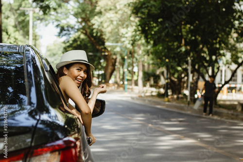 An Asian woman smiled and was happy because she was driving on a holiday trip.
