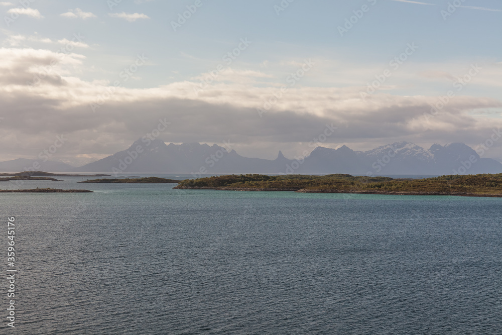 A mystical fjord in Norway with mountains and fog hanging over the water in polar day. midnight sun, selective focus