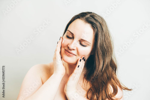 Smiling pleasant woman doing a facial massage.
