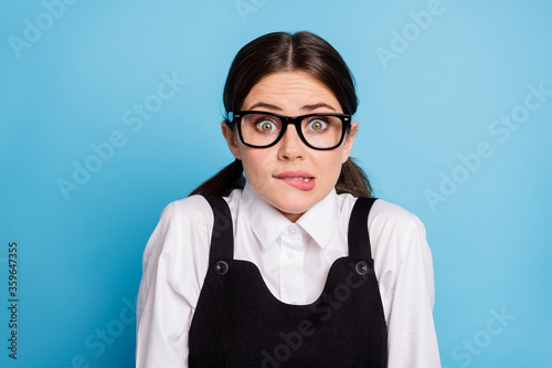 Close-up portrait of her she nice attractive lovely pretty brainy unsure scared brunette schoolgirl nerd geek biting lip worrying isolated over bright vivid shine vibrant blue color background
