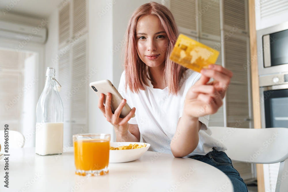 Photo of woman holding credit card and cellphone while having breakfast Photo of woman holding credit card and cellphone while having breakfast