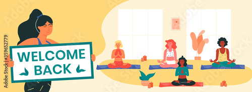 Yoga instructor holds welcome back banner, informing her clients about the resumption of yoga classes after covid-19 lockdown. Women doing padmasana or lotus pose. Physical and mental health.