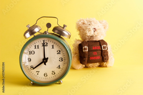 Brown teddy bear with school backpack, yellow background