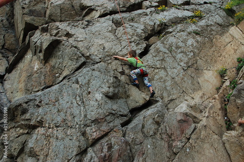 little boy climbs on the rock with rope photo