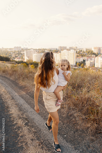 Joyfull young mother spend wonderful holiday time in the forest with her kid. Two blondies, mother and daughter © diignat