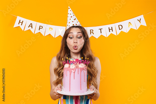Photography Image of happy young woman blowing out candles on birthday torte