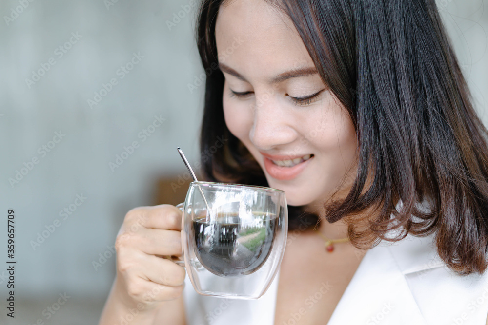 Close up woman drinking hot americano coffee from glass with light in the morning, Selective focus Close up woman drinking hot americano coffee from glass with light in the morning, Selective focus
