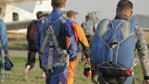 Group professional skydivers goes to the plane, back view