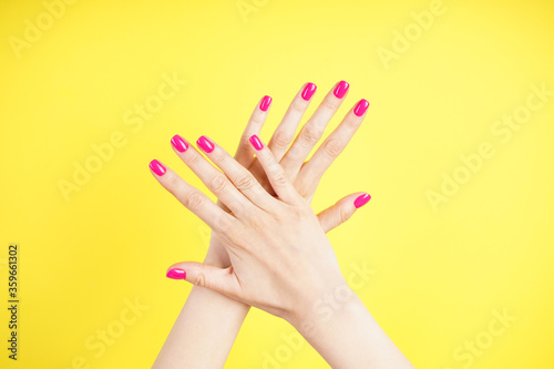 Beautiful hands of a young woman on a yellow background. Beautiful manicure close-up.