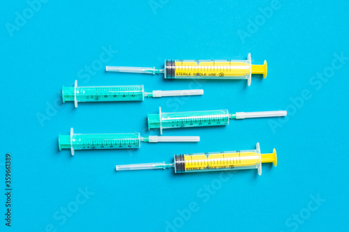Top view of medical syringes with needles at blue background with copy space. Injection treatment concept