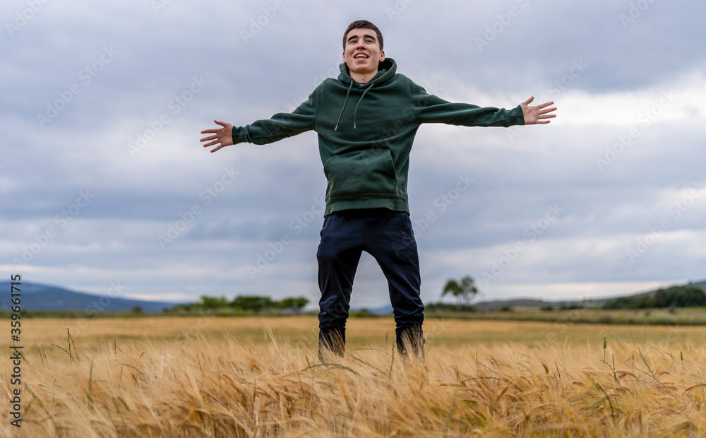 dynamic young guy jumps up and opens his arms next to a cereal field dynamic young guy jumps up and opens his arms next to a cereal field