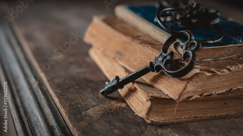 old vintage keys on an old battered book, wooden background. photo
