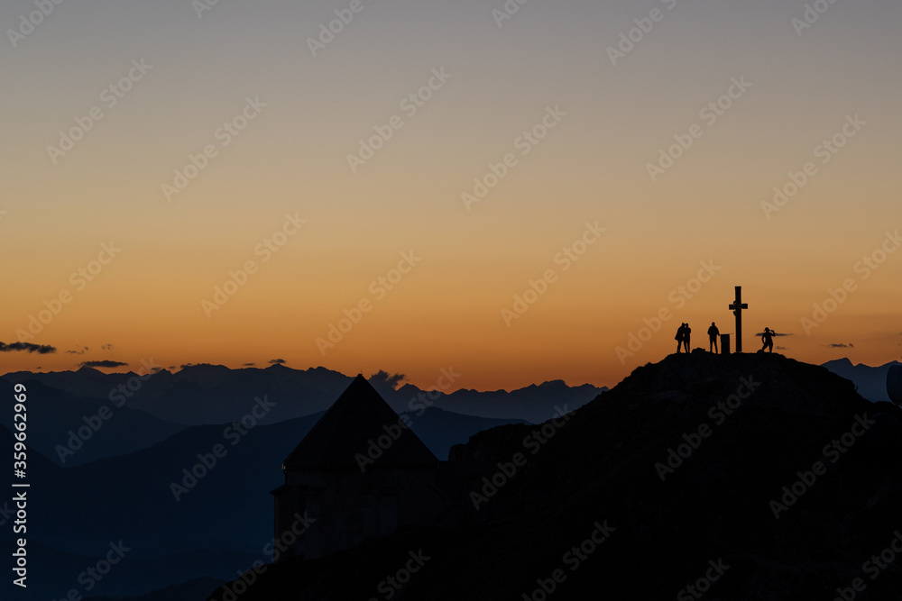 silhouette of hikers on a peak of a mountain top