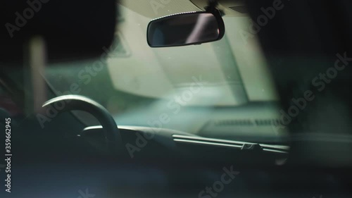 Person hanging white face mask on car rear view mirror